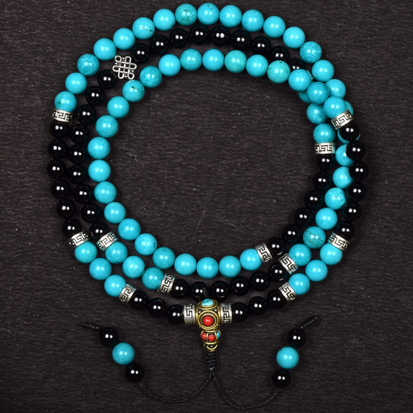 Turquoise and black beaded necklace with a decorative clasp on a dark background