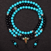 Turquoise and black beaded necklace with a decorative clasp on a dark background