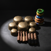 Collection of decorative items including brass plates, wooden sticks, and colorful spools on a dark background.